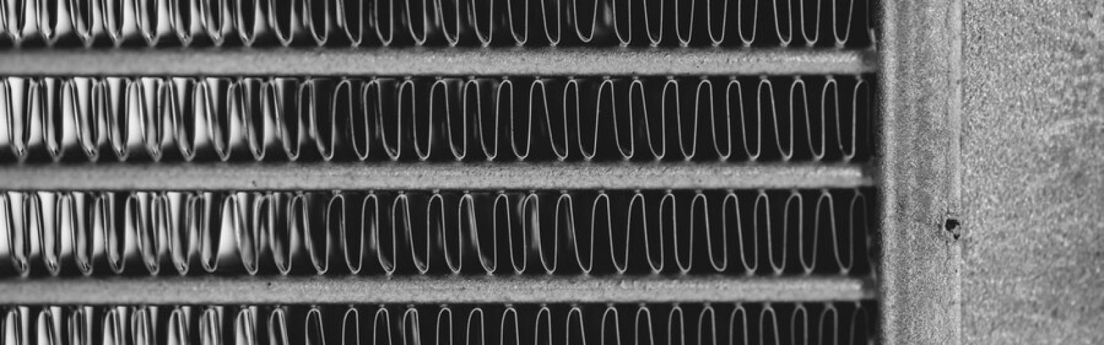 Close-up of an AC evaporator coil, showcasing the intricate metal fins, emphasizing its role in cooling efficiency and HVAC maintenance.