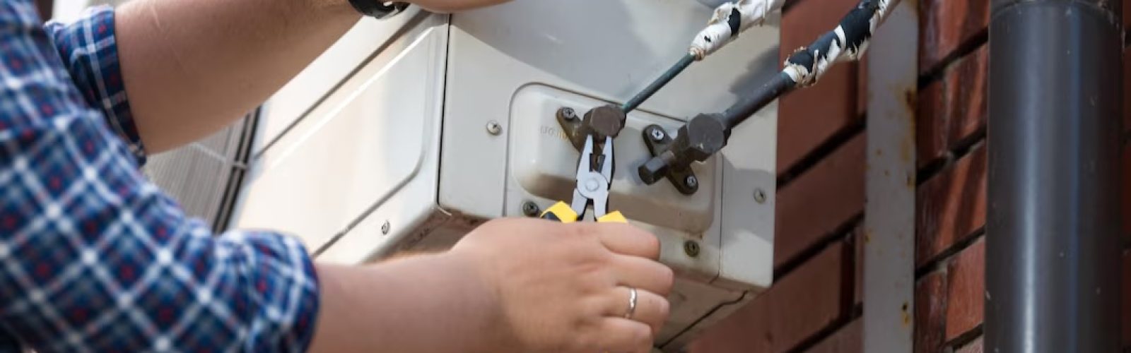 Technician using pliers to service an HVAC unit, focusing on electrical connections, relevant to HVAC maintenance and repair in Moorpark.